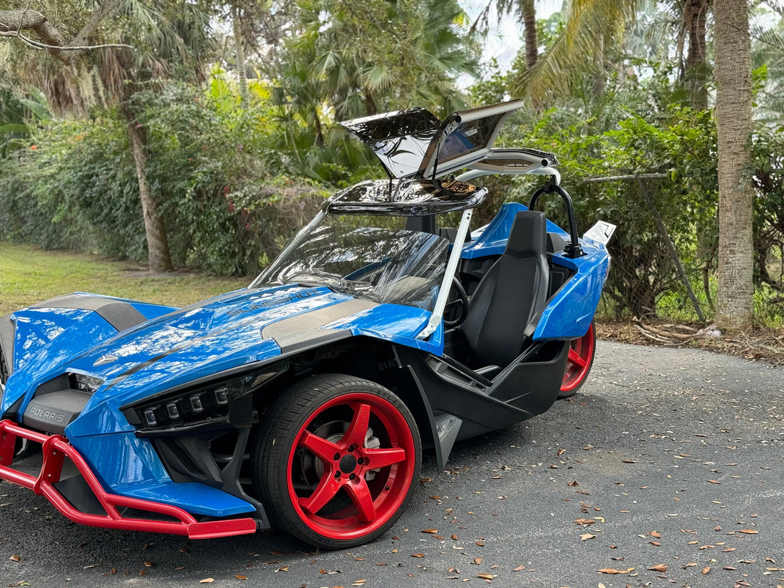 Blue Polaris Slingshot with a Twist Dynamics Gullwing roof and raised side panels.