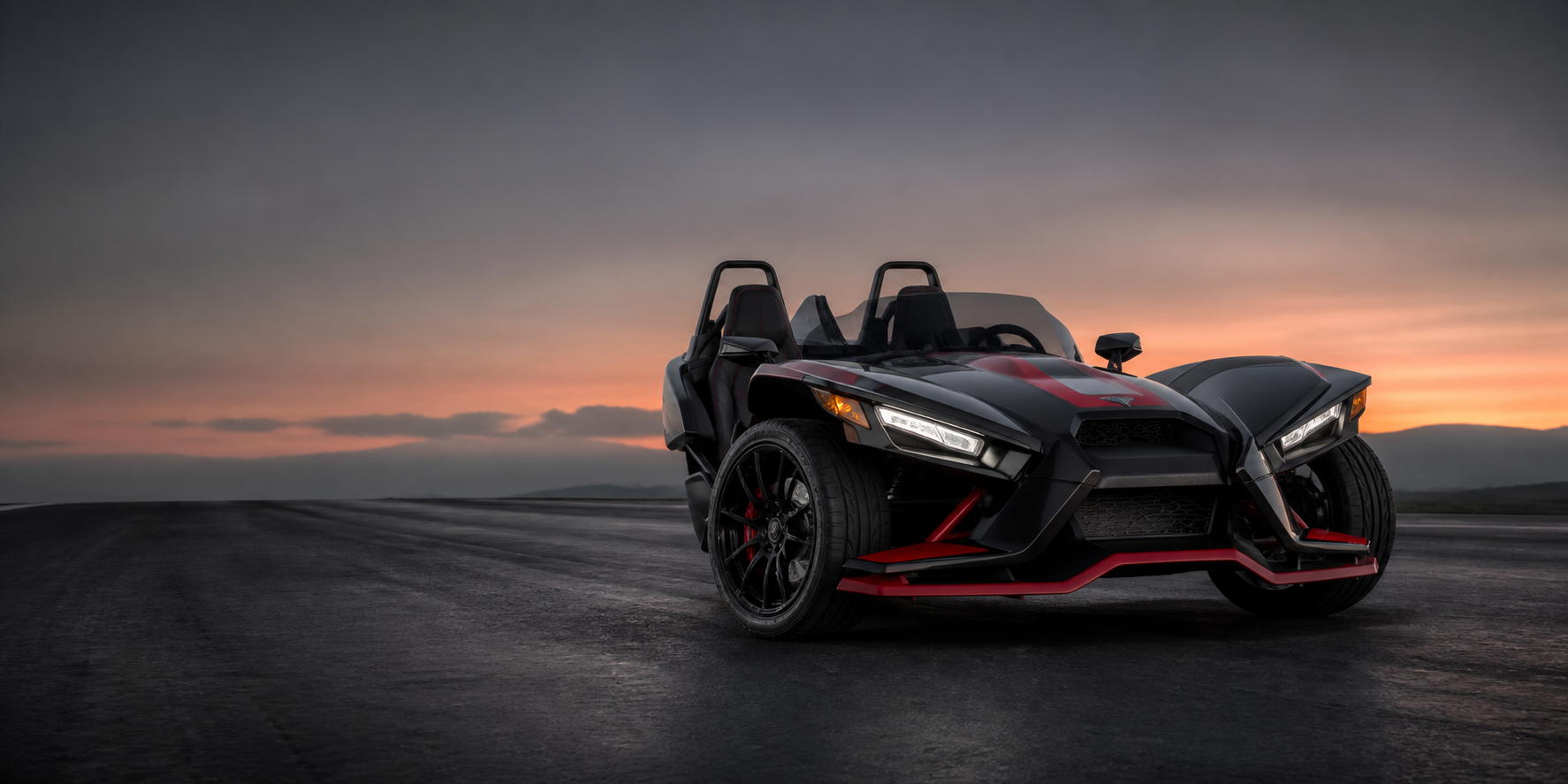 Black and red Polaris Slingshot on an open road at dusk